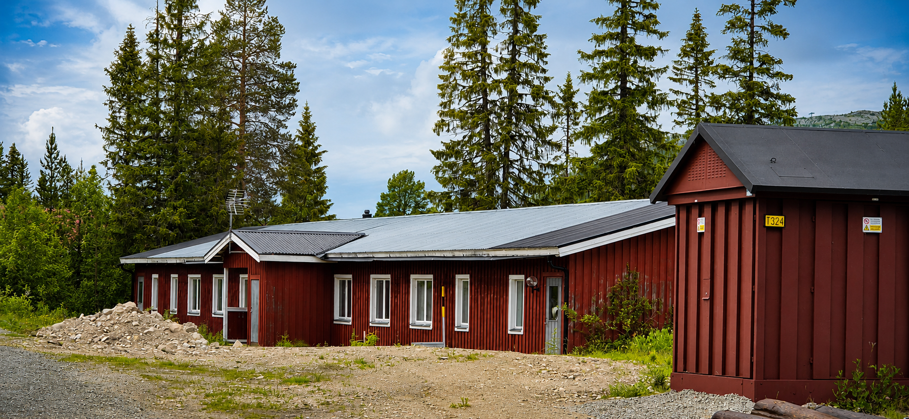 Rött enplanshus i fjällmiljö